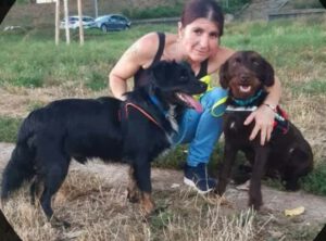 Frau mit 2 Hunden im Arm auf einer Wiese