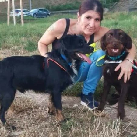 Frau mit 2 Hunden im Arm auf einer Wiese
